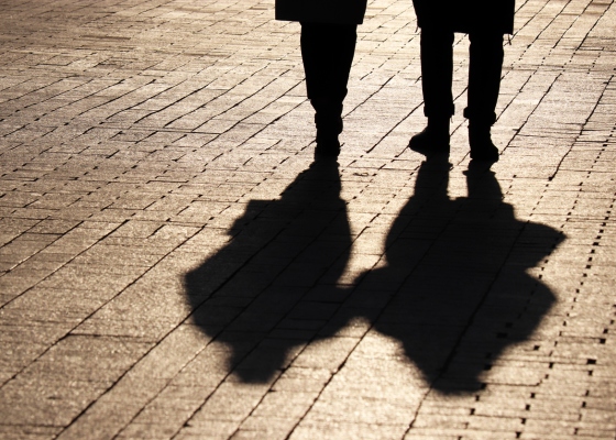 Two people walking together. Visible are their legs and shadows.